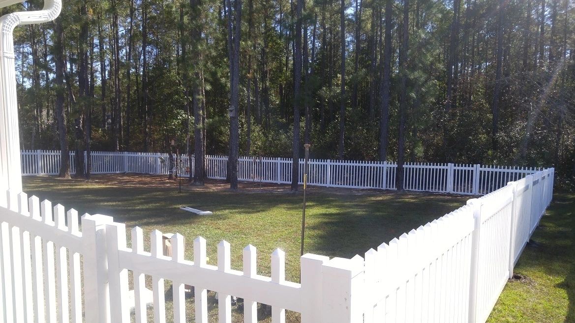 White Picket Fence in Green Grassy Field on a Sunny Day